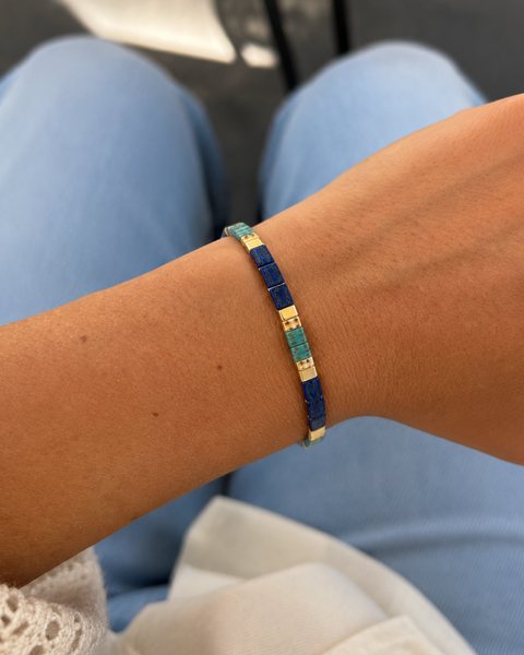 Una muñeca con una pulsera Tile de Rescue Paws hecha de cuentas planas de vidrio