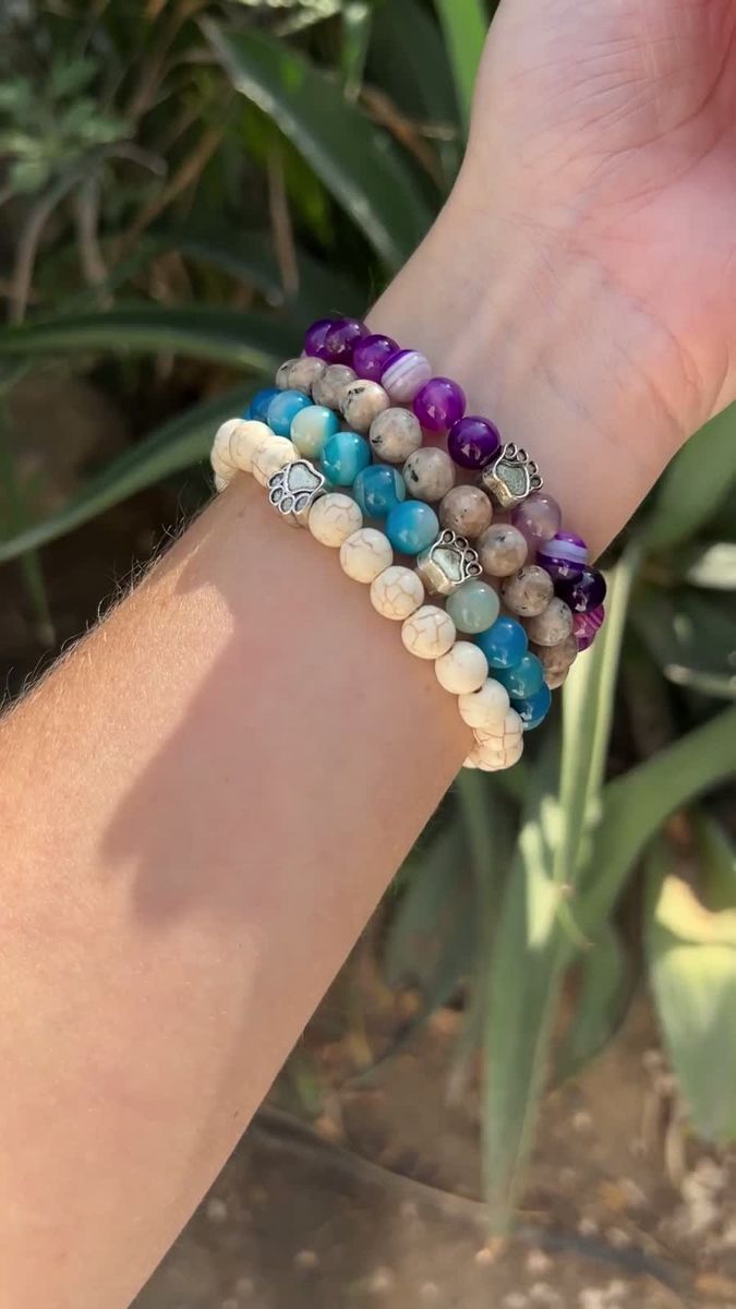 Four Rescue Paws beaded bracelets stacked on a wrist in the sun
