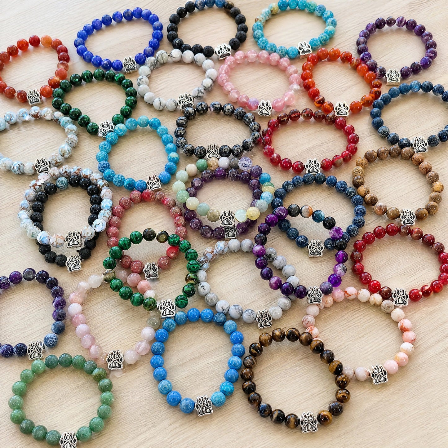 The 38 Rescue Paws beaded bracelets from the Full Collection spread out on a wooden table