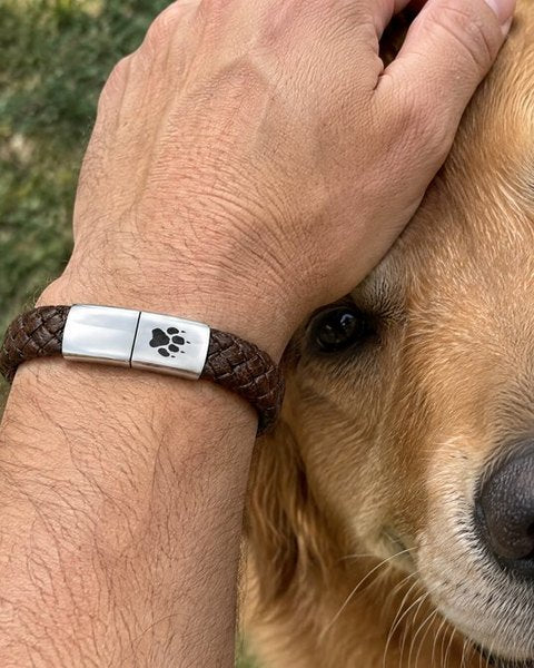 La muñeca de un hombre con una pulsera Rescue Paws para hombre, junto a un perro